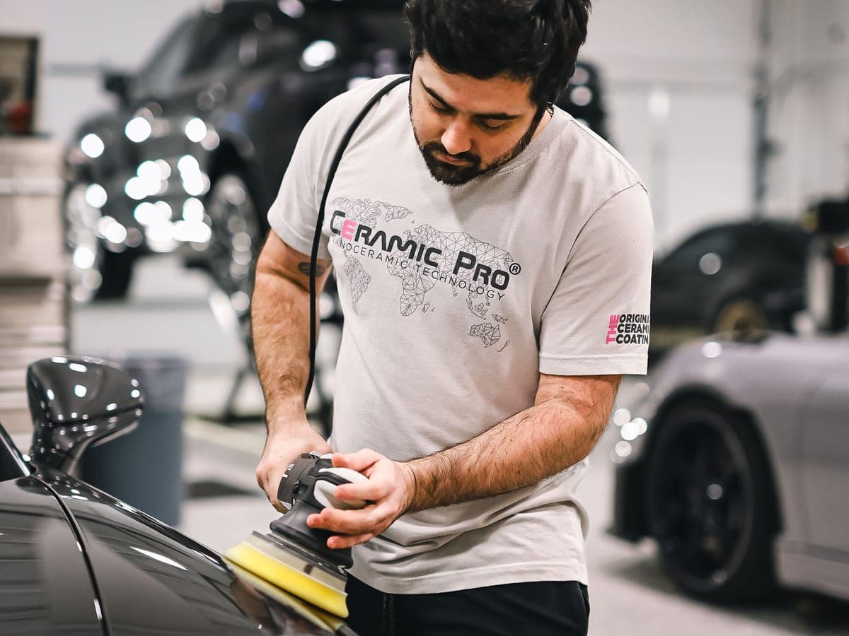 A technician applying a final machine polish to a finished vehicle